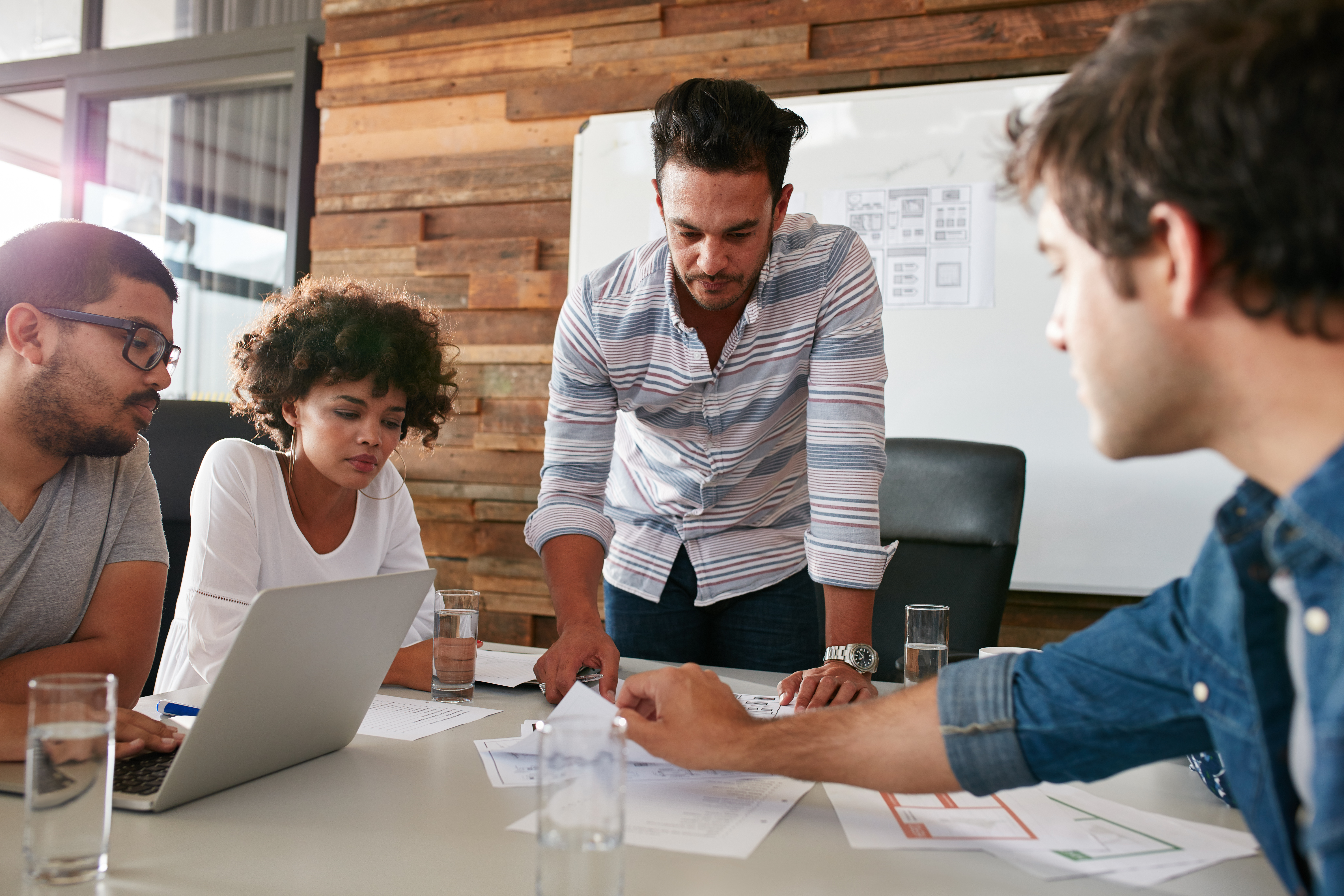 board room meeting scene with four people collaborating